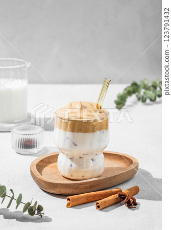 Dalgona coffee in a glass on a light background with shadow and spices. Dalgona coffee in a glass on a light background with shadow and spices. 123791432
