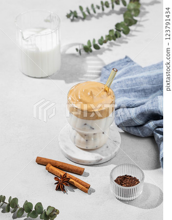 Dalgona coffee in a glass on a light background with milk jug and spices. 123791434