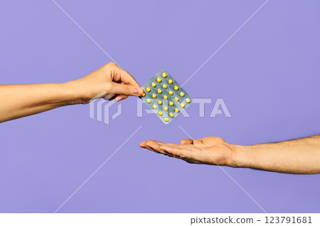 Woman handing over pills medicine in blister packs at man over blue blackground 123791681