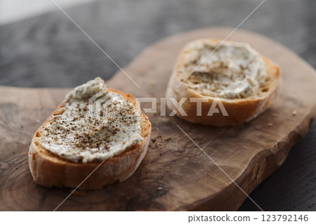 Ciabatta slices with cream cheese and herbs on olive wood board Ciabatta slices with cream cheese and herbs on olive wood board 123792146