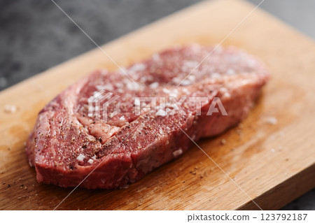 Raw ribeye steak spiced and ready to cook on oak board 123792187
