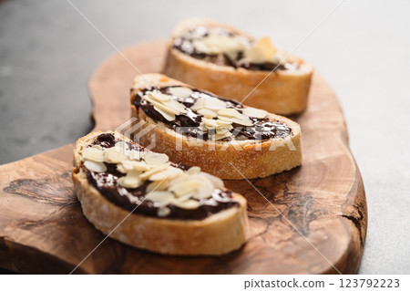 Rustic ciabatta with organic chocolate cream and almond flakes on olive wood board 123792223