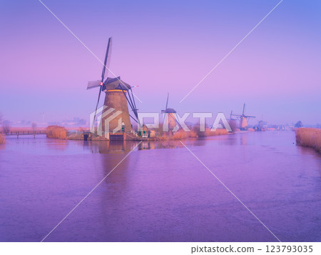 Windmills in the Netherlands during sunrise. Foggy morning. Dutch canals. Windmills in the Netherlands during sunrise. Foggy morning. Dutch canals. 123793035