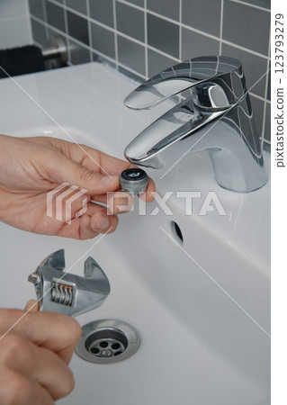man have just removed the aerator from a faucet 123793279