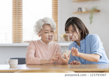 Care staff talking to a senior woman with a smartphone 123793987