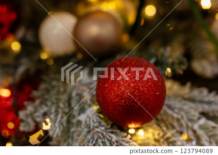 A vibrant red disco ball is beautifully hanging from a christmas tree 123794089