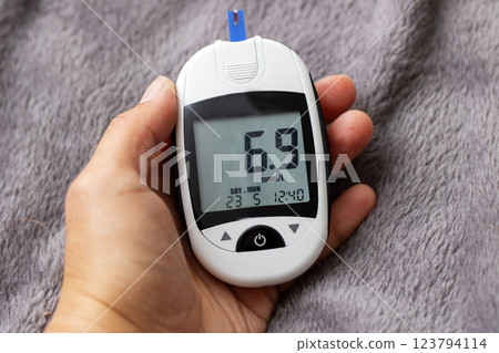 A hand is holding a device with the number 6.9 displayed on its screen 123794114