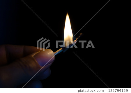 A person is striking a match in total darkness, creating light A person is striking a match in total darkness, creating light 123794139