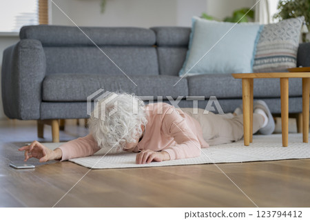 一名老年婦女倒在地上，伸手去拿她的智慧型手機 123794412