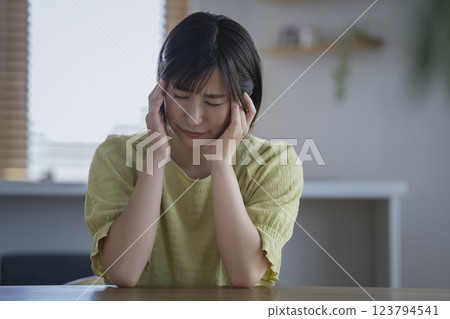 A woman in her 30s holding her head 123794541