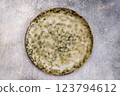 Off-white plate with dark grey spots on light grey background 123794612