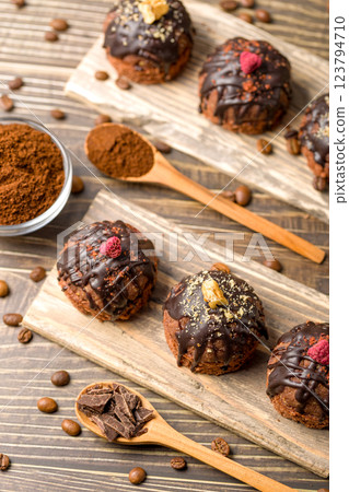 Round chocolate cakes. Decorated with candied raspberries. Wooden background Round chocolate cakes. Decorated with candied raspberries. Wooden background 123794710