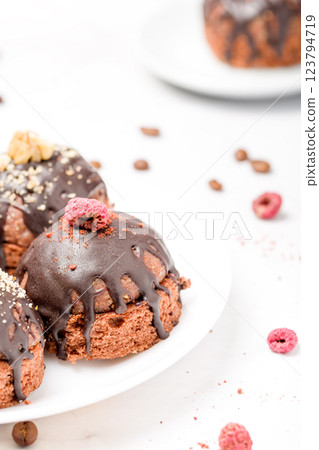 Round chocolate cakes. Decorated with candied raspberries. Light background 123794719