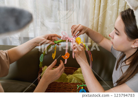 Mother and daughter decorating an Easter basket together. Mother and daughter decorating an Easter basket together. 123794783