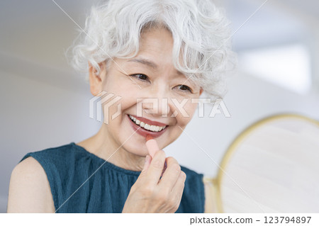 Senior woman applying lipstick in front of a mirror Senior woman applying lipstick in front of a mirror 123794897