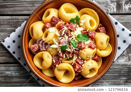 Homemade Mediterranean Tortellini with Artisanal Cured Meats, Aged Parmesan, and Fresh Herbs on Rustic Wooden Table Setting 123796816