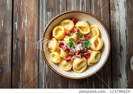 Homemade Mediterranean Tortellini with Artisanal Cured Meats, Aged Parmesan, and Fresh Herbs on Rustic Wooden Table Setting 123796824