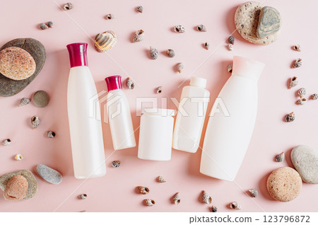 Set of bottles with cosmetic products among stones and shells on pink top view Set of bottles with cosmetic products among stones and shells on pink top view 123796872