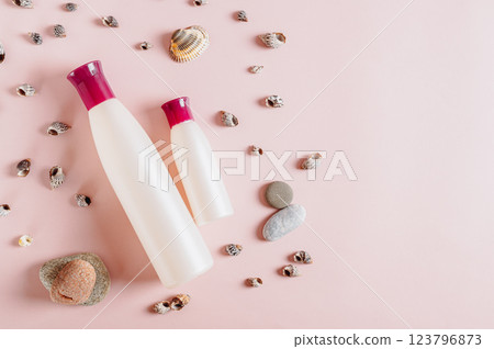 Close up of pair of bottles with cosmetic products among stones and shells on pink top view Close up of pair of bottles with cosmetic products among stones and shells on pink top view 123796873