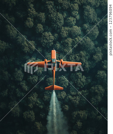 aerial view of orange airplane flying over dense forest, showcasing contrast between vibrant aircraft and lush greenery below 123796894