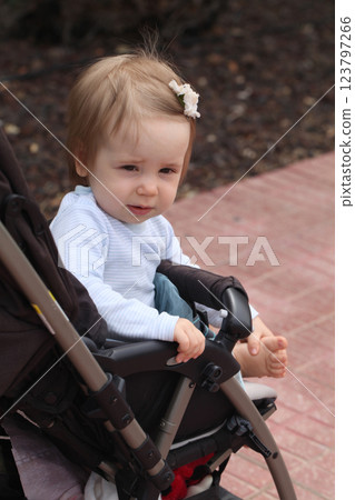 One year old little baby girl smiling in her stroller outdoors One year old little baby girl smiling in her stroller outdoors 123797266