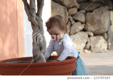 Funny baby girl 1 year old playing in the yard outdoors 123797267