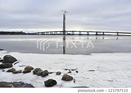 a bridge under construction over a partially frozen body of water in a winter setting 123797533