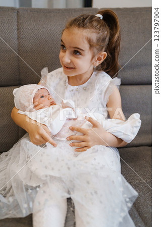 Newborn baby in a hat with pink lace in the arms of his sister in a white dress Newborn baby in a hat with pink lace in the arms of his sister in a white dress 123797904