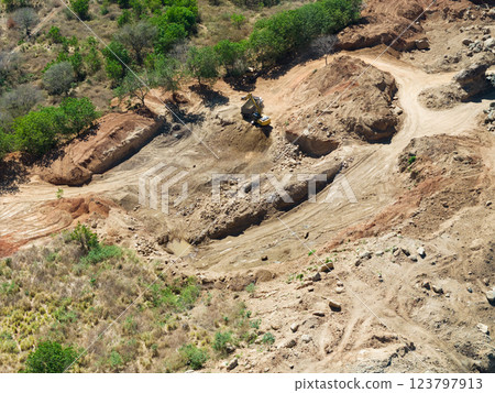Excavation work in dry landscape with sparse vegetation during daylight hours 123797913