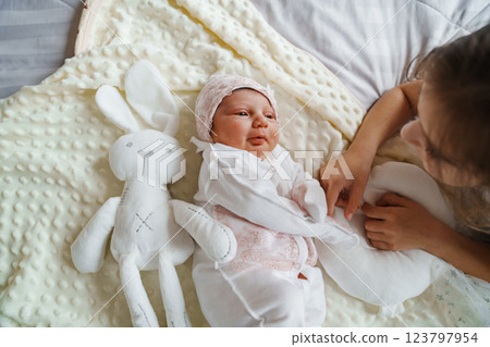 Newborn baby with his sister in a white dress on the bed in the bedroom 123797954