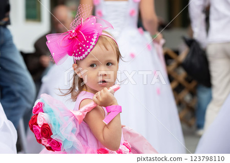 A little girl with a bouquet of the bride in a pink dress with a big bow.A child at a wedding. A little girl with a bouquet of the bride in a pink dress with a big bow.A child at a wedding. 123798110