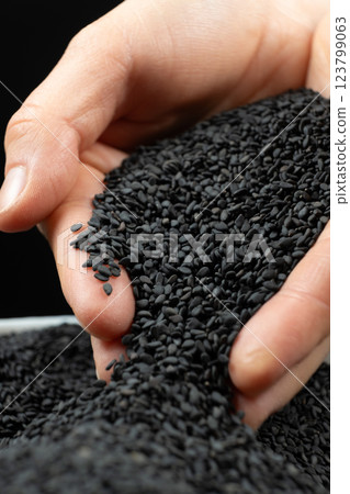 Hands pouring black sesame close-up. 123799063