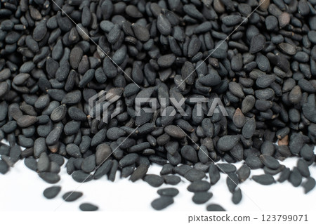 Unpeeled black sesame seeds scattered on a white background macro photography. Unpeeled black sesame seeds scattered on a white background macro photography. 123799071