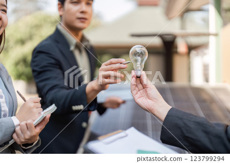 Sustainable business strategies. Professionals discussing energy-saving solutions with a light bulb. Sustainable business strategies. Professionals discussing energy-saving solutions with a light bulb. 123799294