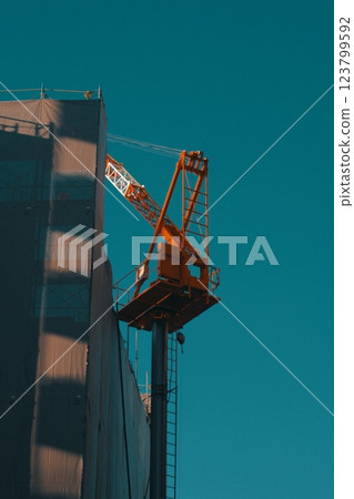 A tower crane at a construction site stretching into the blue sky 123799592