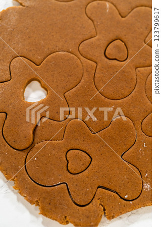 Overhead view of gingerbread dough rolled out with flower and heart cookie cutouts. Overhead view of gingerbread dough rolled out with flower and heart cookie cutouts. 123799617