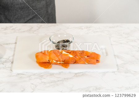 Smoked salmon roll is coated with a layer of black and white sesame seeds, enhancing its flavor and texture. 123799629