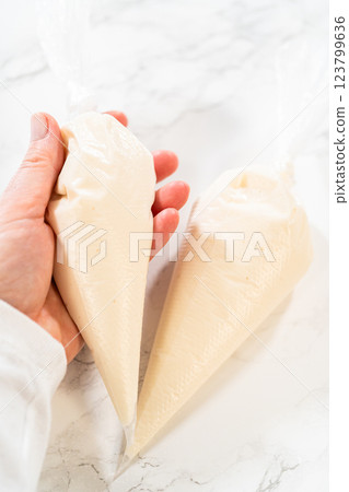 Two piping bags filled with smooth royal icing, placed on a marble surface alongside scissors, ready for festive cookie decorating. Two piping bags filled with smooth royal icing, placed on a marble surface alongside scissors, ready for festive cookie decorating. 123799636