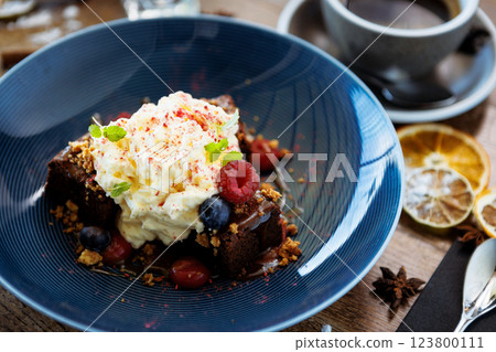 Brownie cake with salted caramel. Anglaise foam, raspberry sauce, praline nut and fresh berry. Delicious sweet dessert food closeup served for lunch in modern gourmet cuisine restaurant Brownie cake with salted caramel. Anglaise foam, raspberry sauce, praline nut and fresh berry. Delicious sweet dessert food closeup served for lunch in modern gourmet cuisine restaurant 123800111