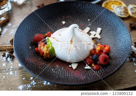 Pavlova berry cake with passion cream, strawberry, meringue. Delicious sweet dessert food closeup served for lunch in modern gourmet cuisine restaurant Pavlova berry cake with passion cream, strawberry, meringue. Delicious sweet dessert food closeup served for lunch in modern gourmet cuisine restaurant 123800112