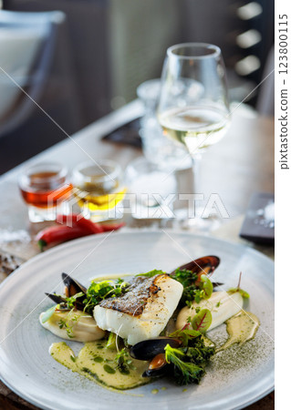 Cod fillet with cauliflower cream, asparagus, clam-wine sauce and mussles. Delicious seafood fish closeup served on a table for lunch in modern cuisine gourmet restaurant Cod fillet with cauliflower cream, asparagus, clam-wine sauce and mussles. Delicious seafood fish closeup served on a table for lunch in modern cuisine gourmet restaurant 123800115