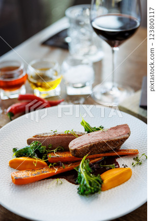 Duck fillet with sweet potato cream, roasted carrots, kale, beet-port sauce on white plate. Grilled and roasted poultry closeup served on a table for lunch in modern cuisine gourmet restaurant. 123800117