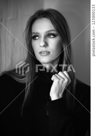 Black and white portrait captures a woman in a black sweater, softly lit. Her confident gaze and delicate hand gesture create an elegant, cinematic, and timeless atmosphere Black and white portrait captures a woman in a black sweater, softly lit. Her confident gaze and delicate hand gesture create an elegant, cinematic, and timeless atmosphere 123800133