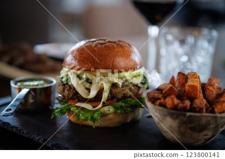 Healthy veggie burger with fresh lettuce, tomato, cheese, and sauce on a toasted bun. Paired with crispy sweet potato fries and a small cup of dip. Ideal for a nutritious meal Healthy veggie burger with fresh lettuce, tomato, cheese, and sauce on a toasted bun. Paired with crispy sweet potato fries and a small cup of dip. Ideal for a nutritious meal 123800141