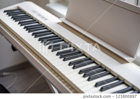 White digital piano synthesizer with sleek keys and modern design, ready for music production and performance. Concept of creativity, sound technology, and professional instrumental equipment 123800897