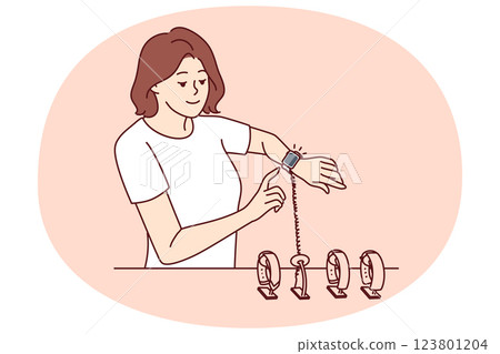 Woman tries on smart watch or fitness bracelet, wanting to choose device for playing sports Woman tries on smart watch or fitness bracelet, wanting to choose device for playing sports 123801204