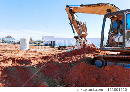Heavy excavator action digs trench for drainage pipe at construction site, moving dirt reshaping landscape during excavation work Heavy excavator action digs trench for drainage pipe at construction site, moving dirt reshaping landscape during excavation work 123801320