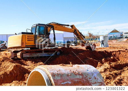 Heavy excavator operates at construction site, moving soil during preparing ground for new structures. 123801322