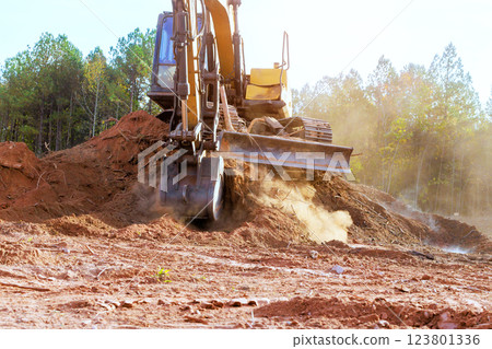 Heavy excavator is actively moving dirt, debris at construction site surrounded by work equipment 123801336