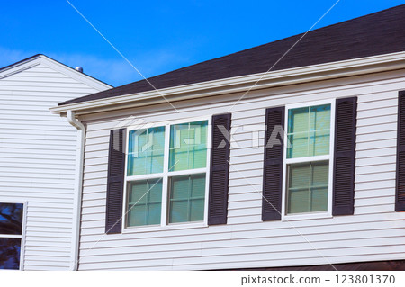Modern house features white siding, black shutters, large windows enhances appearance of this attractive residential building at American town Modern house features white siding, black shutters, large windows enhances appearance of this attractive residential building at American town 123801370